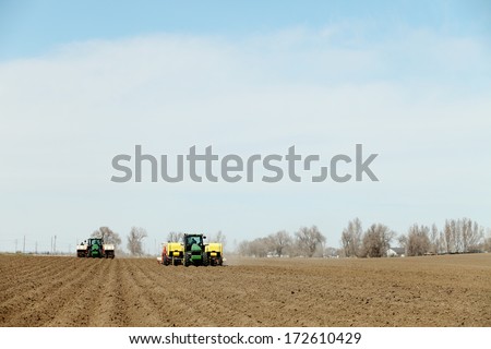 Fort Hall, Idaho, USA.  Jul 12, 2013  Tractors and other farm machinery working in the fields planting Famous Idaho Potatoes.