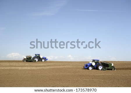 Hamer, Idaho, USA May 11, 2011 Farmers and field hands use farm machinery in the field harvesting russet potatoes.  The potatoes are dug by a potato combine, and taken to a cellar for storage.