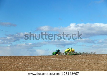 Ririe, Idaho USA-Apr. 22, 2013- Farmers and field hands use farm machinery in the field to plow the land in preparation for planting wheat.  This irrigated farm land,will soon be a lush green field.