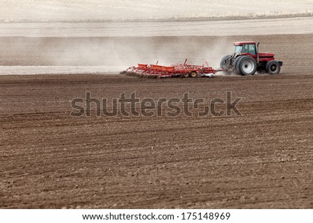 Ririe, Idaho USA-Apr. 11, 2012- Farmers and field hands use farm machinery in the field to plow the land in preparation for planting wheat.  This irrigated farm land,will soon be a lush green field.