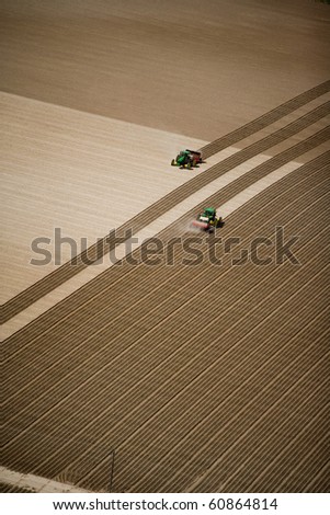 An aerial view of two tractors working in the field planting.  A great background image with a lot of area for copy.