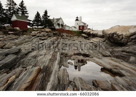 A view of the Pemaquid lighthouse located on the coast of Maine, reflected in a tidal pool.
