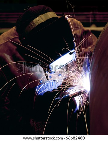 A welder welding the top on a pressure vessel.