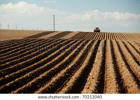 A tractor planting a farm field in the spring.