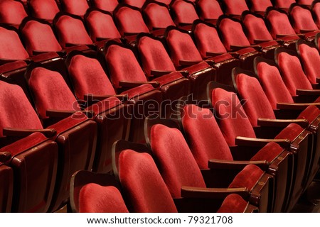 Rows of red velvet theater seats in an old Vaudeville style theater.