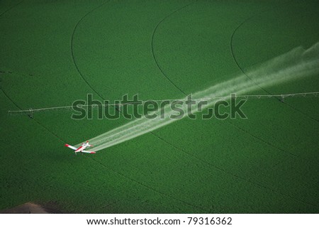 Aerial View of a crop duster spraying a farm field