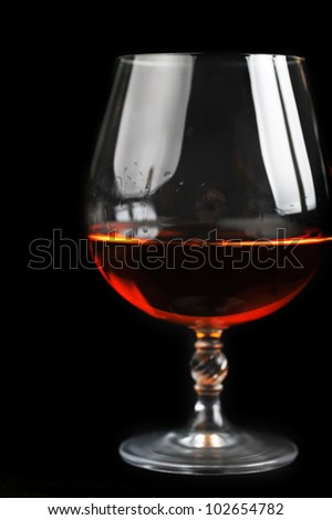 snifter of  brandy in  elegant  glass.  black background