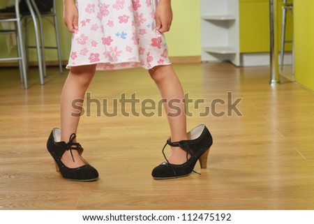 Funny little girl in her mother\'s big shoes