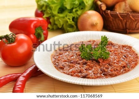 Bowl of chili with peppers,  beans and  basket of bun