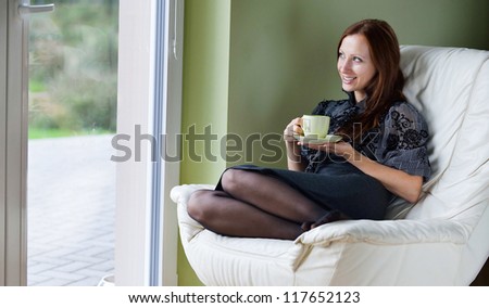 young woman sits on chair and drinking hot coffee