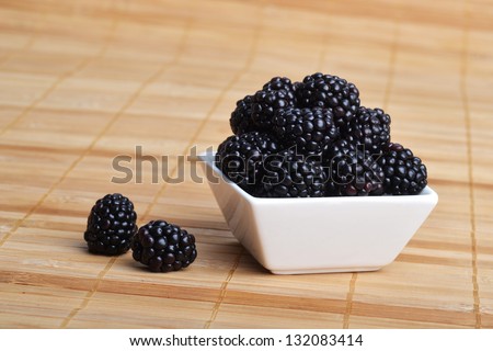 blackberry in white ceramic bowl on wooden background