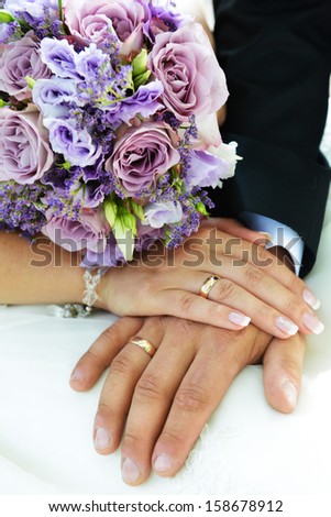 2 hands with wedding rings and flowers