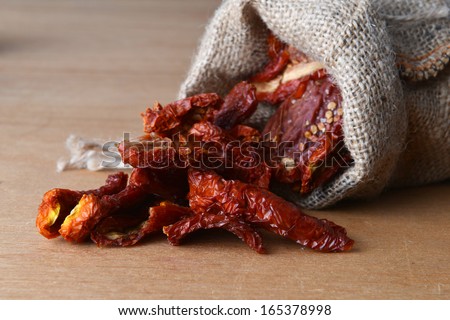 Dried tomatoes got enough sleep from canvas bag at wooden background