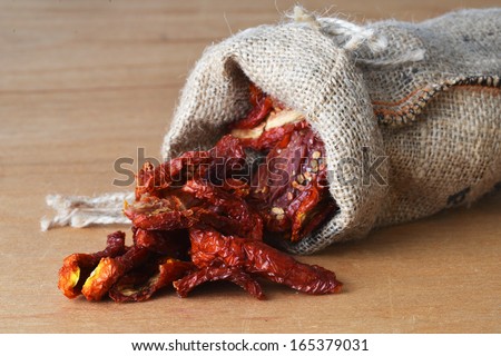 Dried tomatoes got enough sleep from canvas bag at wooden background