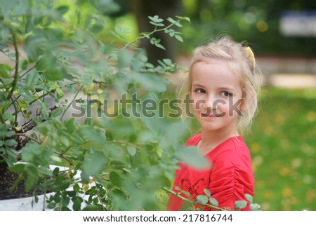 little girl near flower's bush in park.