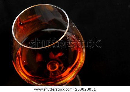 snifter of  brandy in  elegant  glass.  black background