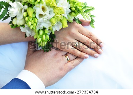 Hands with wedding rings and bouquet