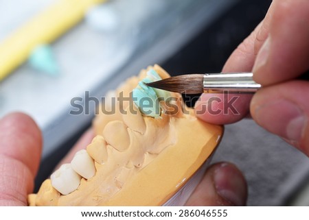 dental technician working on false teeth. table with dental tools.