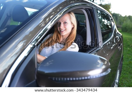 Smiling woman sit in car.car stands on green glade