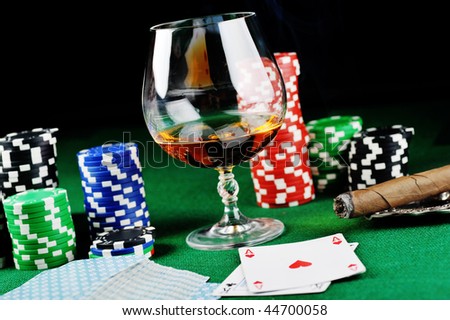 Cigar, chips for gambling , drink and playing cards on green