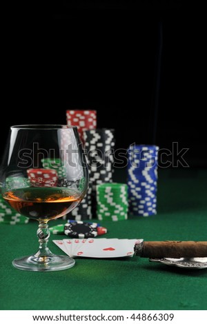 Cigar, chips for gambling , drink and playing cards on green