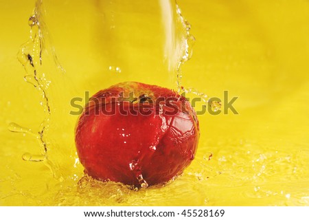 apple and water splashes on  yellow close up
