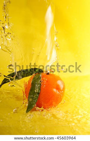 tangerine and water splashes on yellow, close up