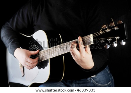 Young man playing on black  guitar.