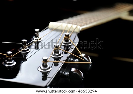 Details of  acoustic black guitar. neck, nut, frets, strings.