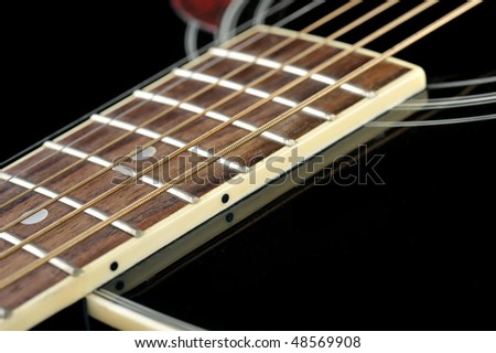 Details of  acoustic black guitar. neck, nut, frets, strings.