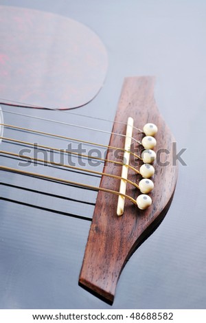 Detail of an acoustic black guitar with the strings