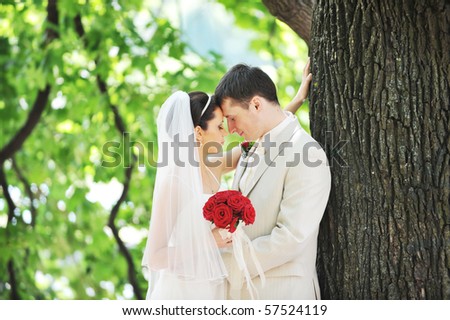 groom and bride in white dress on background of green trees