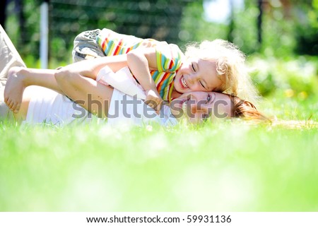 Beautiful young mother with her  daughter playing on grass . summer.