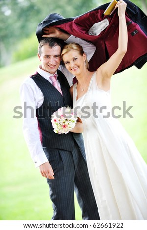 cheerful young pair in  wedding day hides from  rain