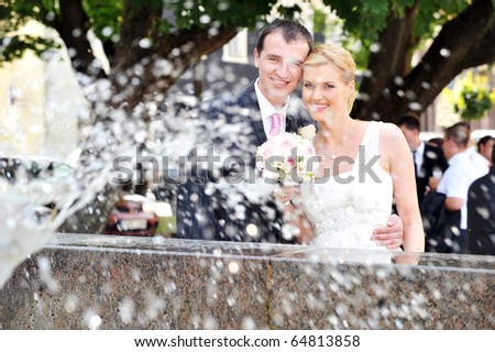 bride and groom stand near  fountain