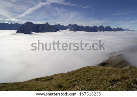 many mountain peaks in the sun with clouds