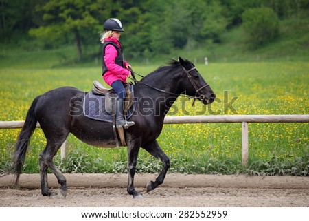 riding girl with black pony at spring time