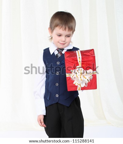 Little smart boy in suit holding red present box