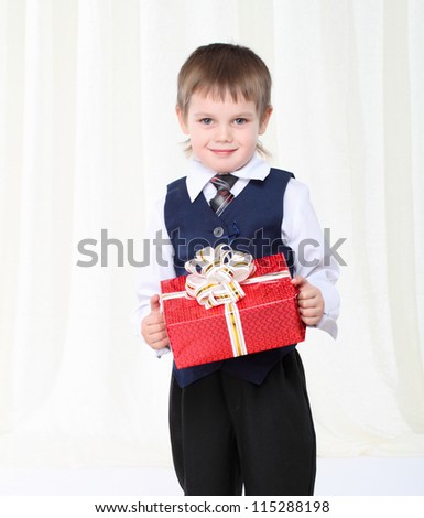 Little smart boy in suit holding red present box
