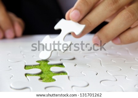 Hand embed missing puzzle piece into place, green space concept