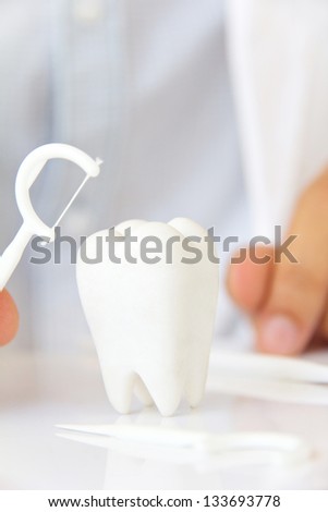hand holding dental floss with molar, flossing teeth concept