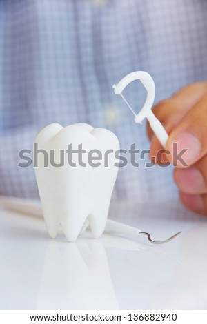 hand holding dental floss with molar, flossing teeth concept