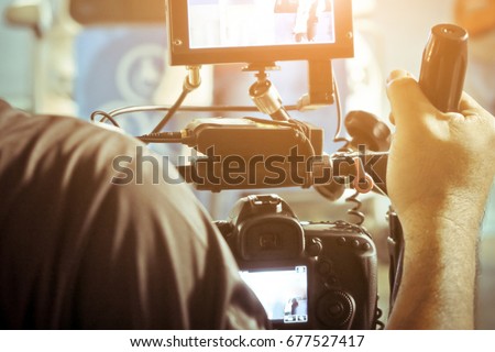 Cameraman with his video camera shooting, Hands Adjusting Camera,film production crew,behind the scenes background.