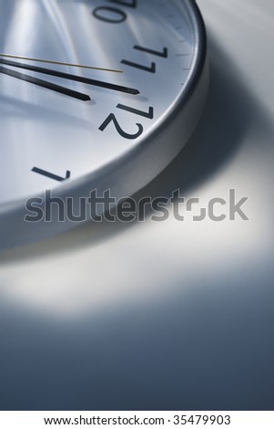A view of the top portion of a clock that reads one minute to twelve.  Vertically framed shot.