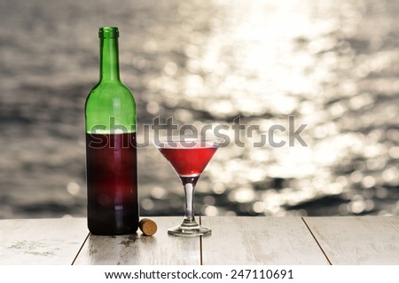 Bottle and glass of red wine on the table against the sea
