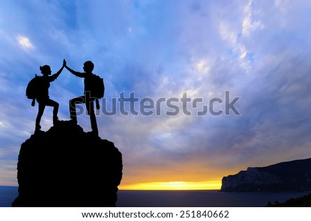 Silhouette of the team on the peak of mountain. Sport and active life of people man and girl