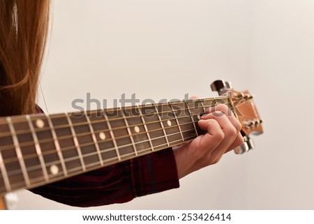 woman\'s hands playing acoustic guitar, close up. Playing acoustic guitar girl or woman with long hair by fingers. finger position on the chord. selective focus image