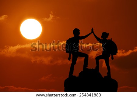 Silhouette of the two people man girl success on the peak of mountain. Sport and active life sunset landscape