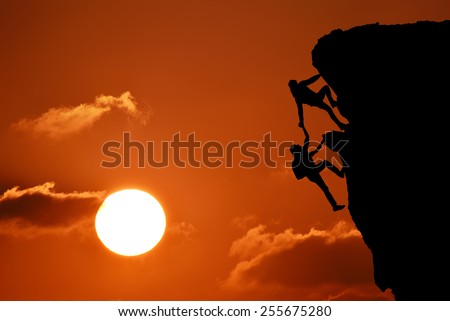 The joint work teamwork of two men travelers help each other on top of a mountain climbing team, a beautiful sunset landscape with big sun,sunset