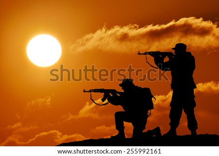 Silhouette of military two soldier or officer with weapons at sunset. shot, holding gun, colorful sky, mountain, background, team